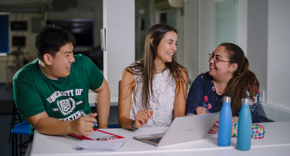 Postgraduate students working at a table and sharing a joke