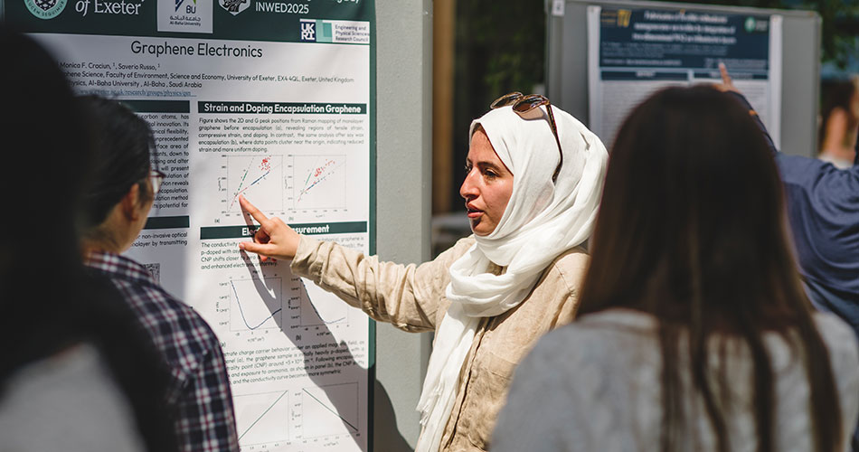 A woman wearing a hijab and glasses points to a poster titled 
