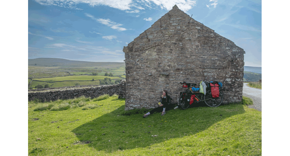People sitting in the shade of a farm building or house