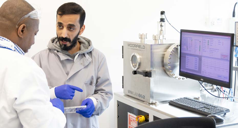 Researchers next to some machinery in a lab discussing results