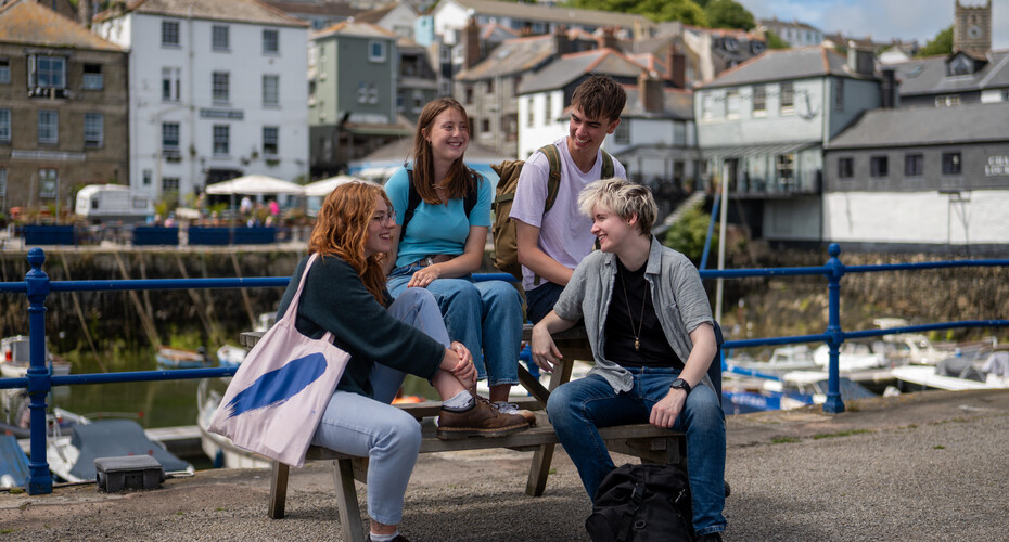 Four students in Falmouth talking on a bench