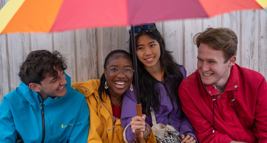 Four students under an umbrella in Teignmouth