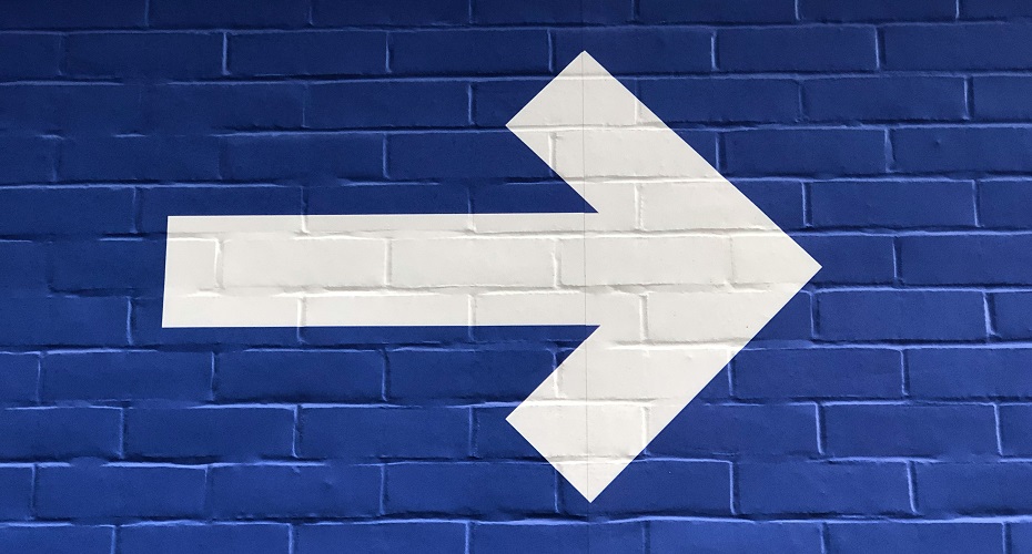 A white arrow painted on a blue brick wall