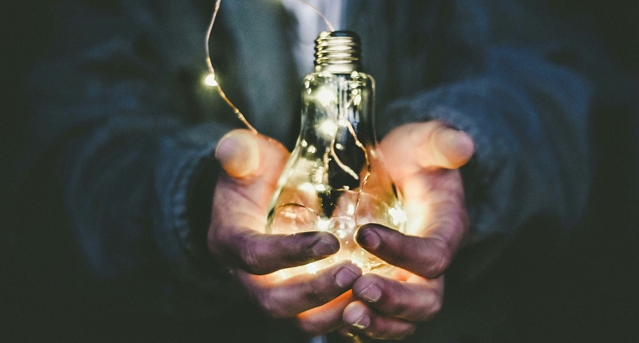 Hands holding an incandescent lightbulb