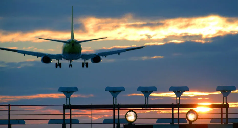A plane soaring above a runway, preparing for takeoff against a clear blue sky.