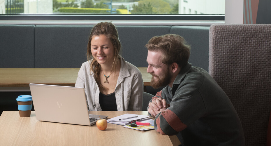 Two students working together on a laptop